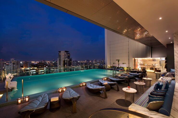 Rooftop infinity pool and lounge at night, representing luxury amenities