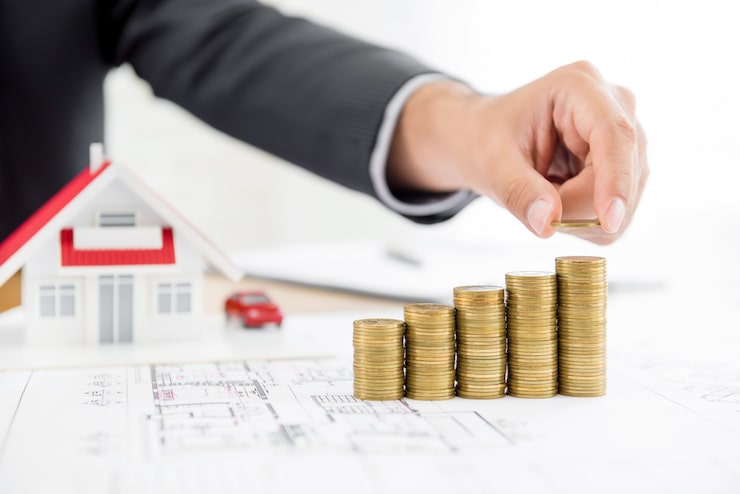 Coins stacked beside a house model, representing the cost of a home